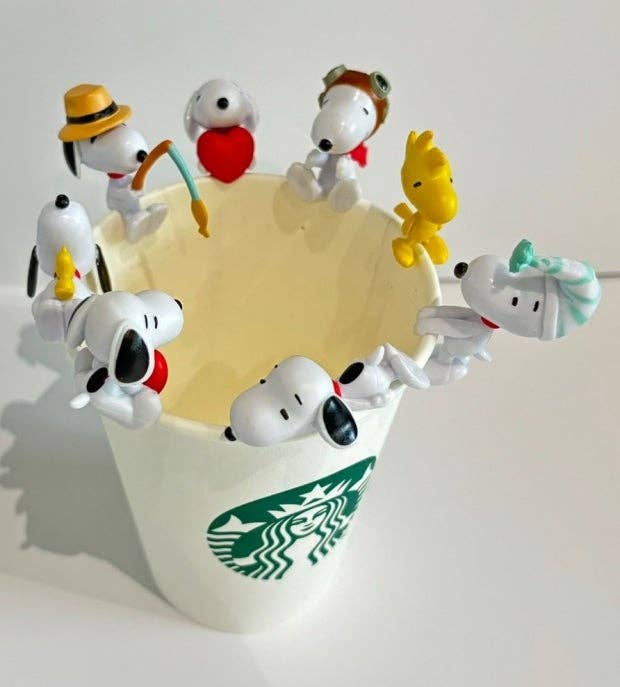 K-Wonderland Peanuts Snoopy cup figures blind box set perched around a white Starbucks cup rim in various costumes and poses