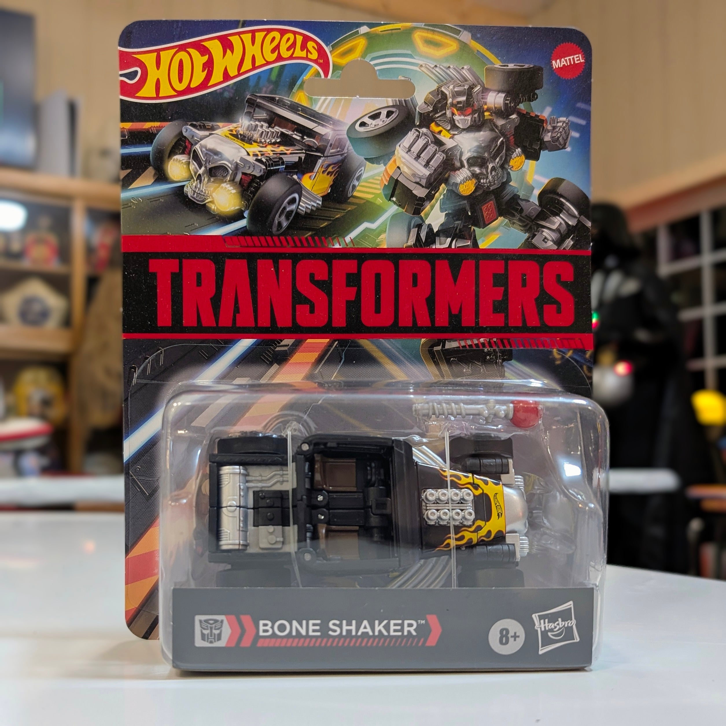 Hasbro Transformers Hot Wheels Bone Shaker action figure in vehicle form with packaging and robotic artwork background