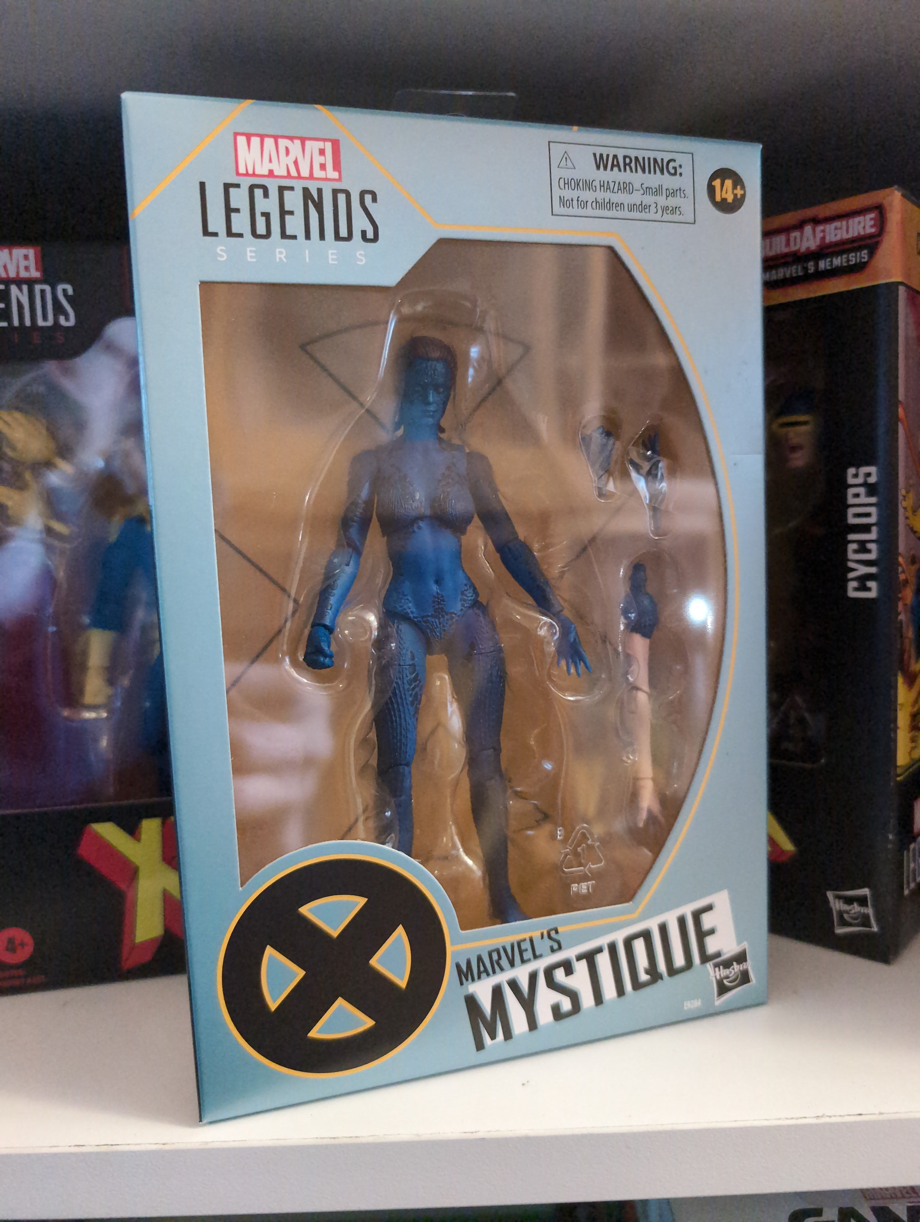 Hasbro Marvel Legends Mystique 6-inch action figure in packaging with accessories on display shelf.