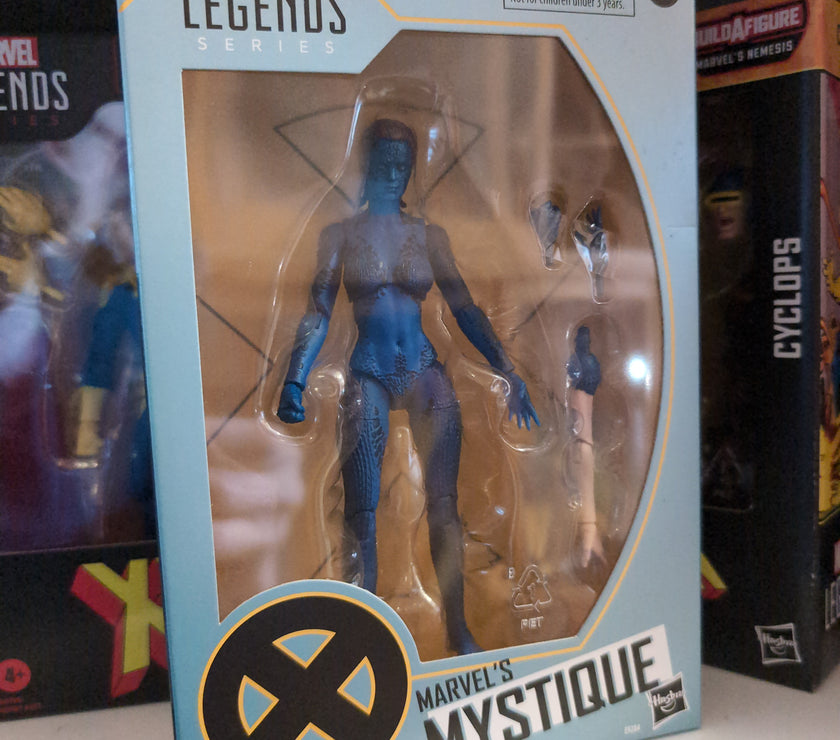 Hasbro Marvel Legends Mystique 6-inch action figure in packaging with accessories on display shelf.