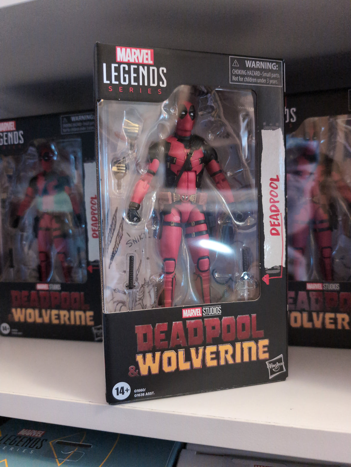 Deadpool action figure in red and black suit packaged in Marvel Legends box by Hasbro on a store shelf