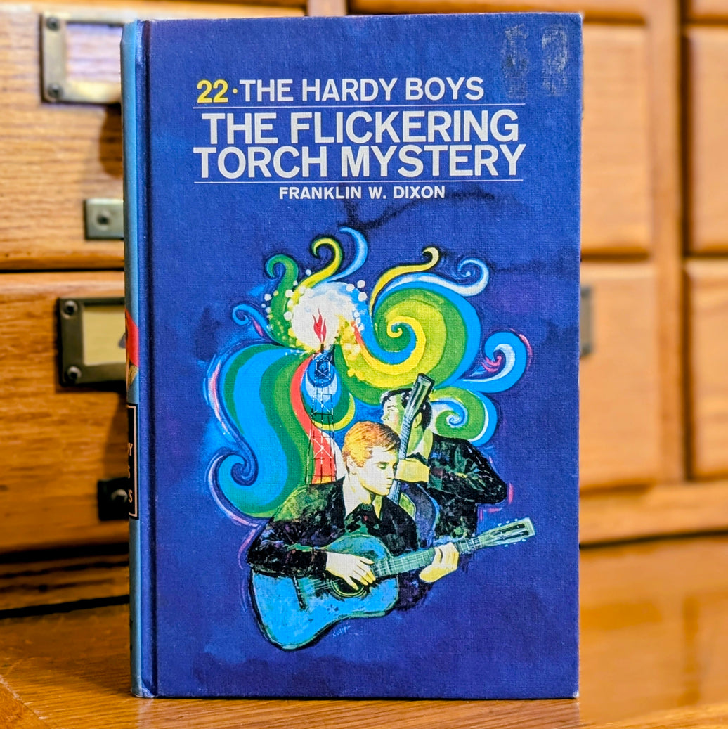 Vintage Hardy Boys book The Flickering Torch Mystery by Grosset & Dunlap Inc with colorful cover art on blue background
