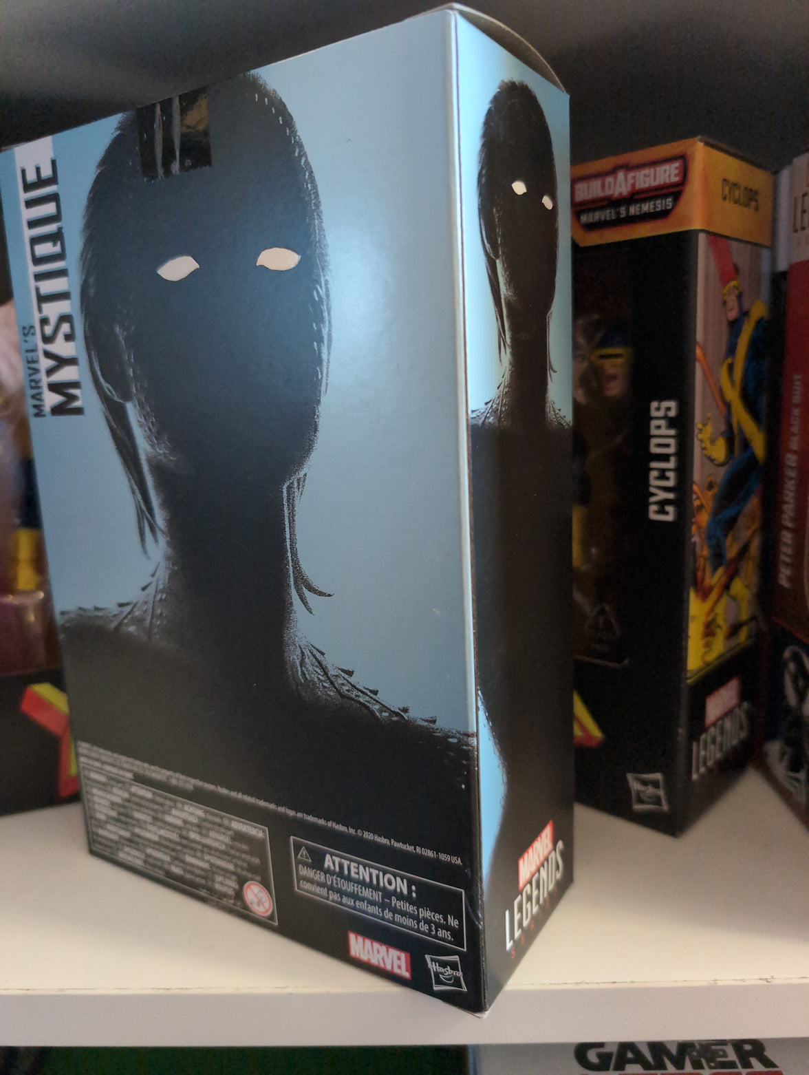 Hasbro Marvel Legends Mystique 6-inch action figure packaging showing shadowed silhouette with white eyes.
