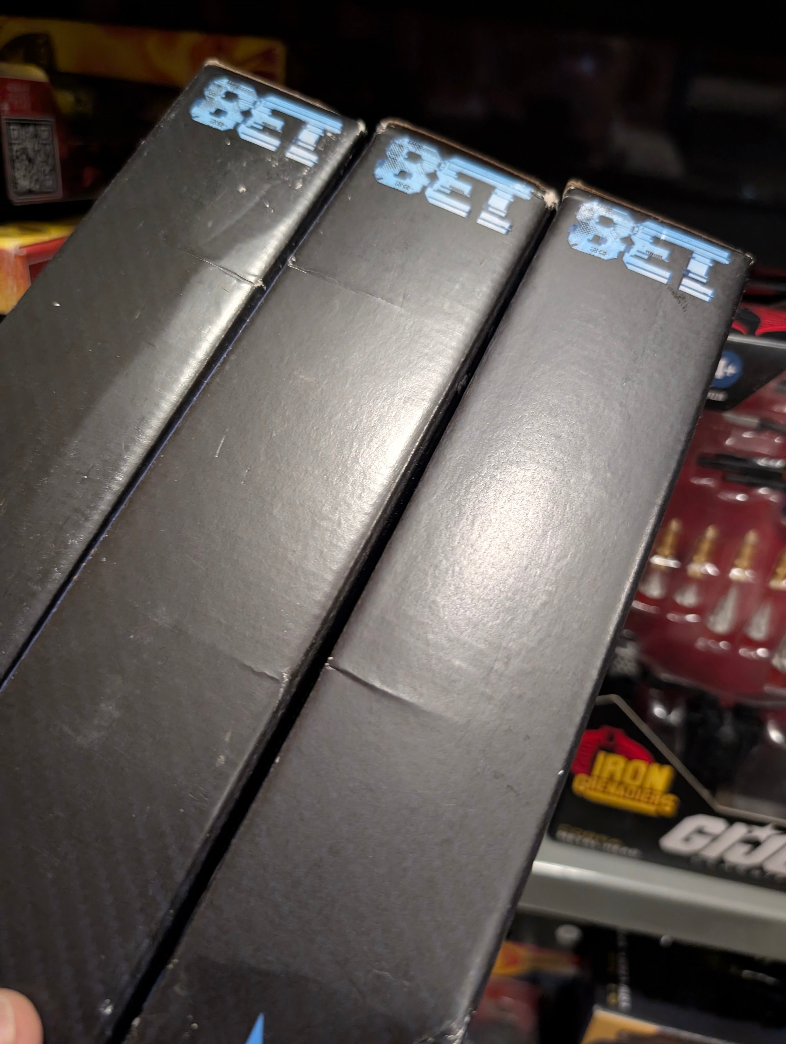 Stack of three black BET branded boxes shown with part of Hasbro GI Joe Night Force figures in background