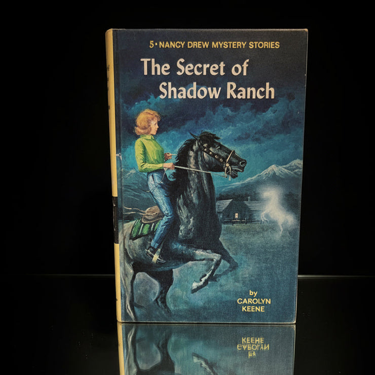Vintage 1965 Grosset & Dunlap Nancy Drew book The Secret of Shadow Ranch by Carolyn Keene standing on black surface