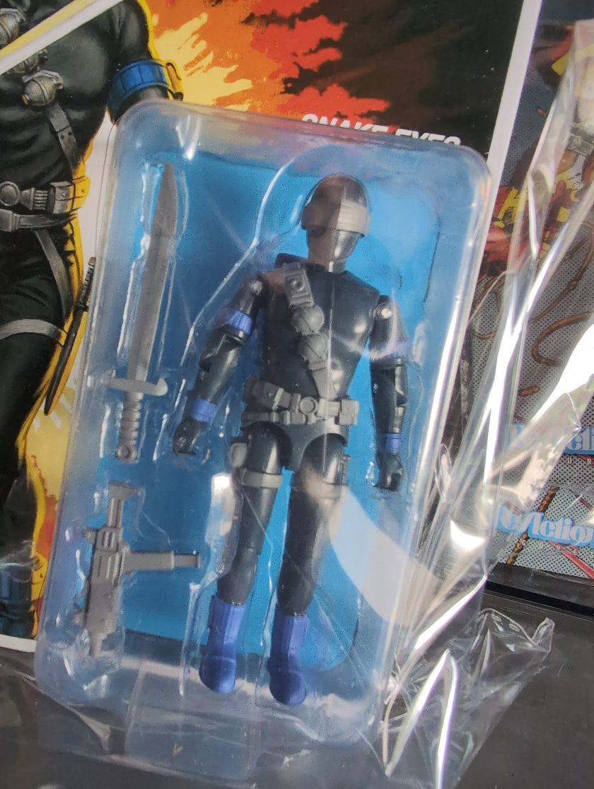 Hasbro Snake Eyes G.I. Joe ReAction+ figure in black tactical gear with sword and blaster accessories in packaging